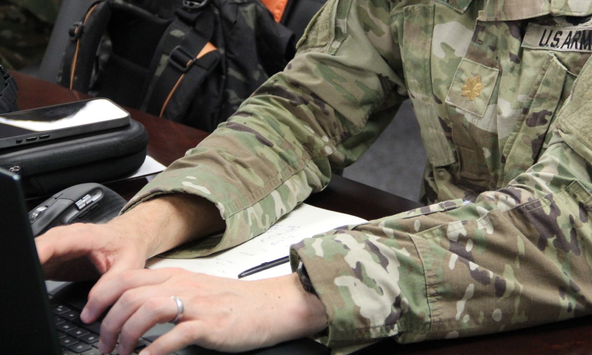 A service member working at a laptop, the lead image for the Modern War Institute article.
